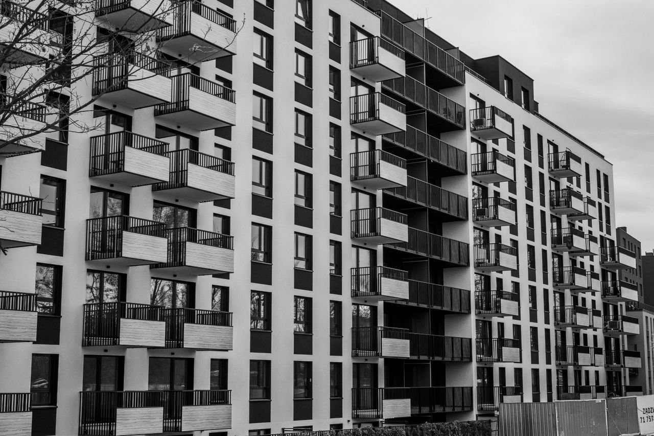 services-02 Black and white photo of a contemporary apartment building with multiple balconies.