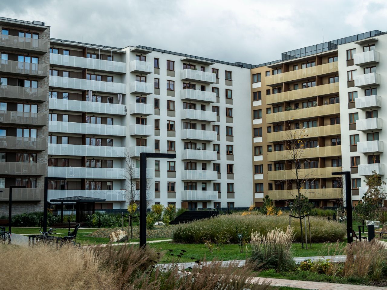 The Art of Drawing Readers In: Your attractive post title goes here A modern apartment building surrounded by landscaped greenery under a cloudy sky.