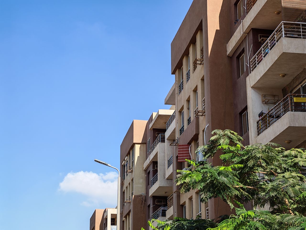 Mastering the First Impression: Your intriguing post title goes here Urban apartment building against a bright blue sky with foliage in the foreground.
